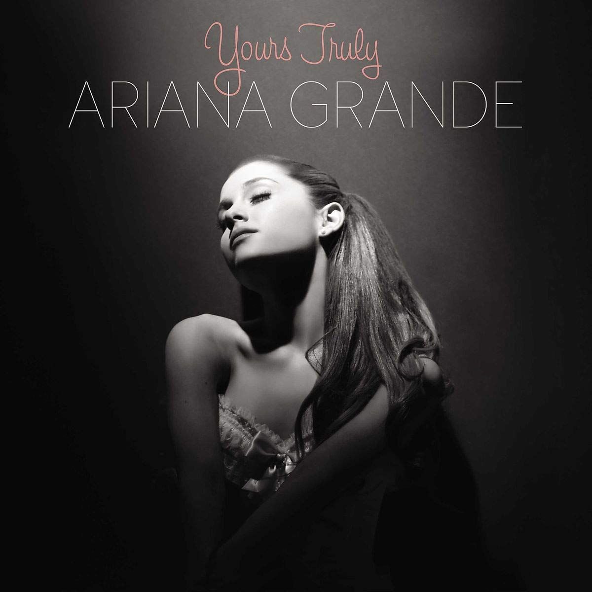 Album cover for Yours Truly by Ariana Grande showing Ariana in black and white, seated with long dark hair, wearing a strapless dress and looking away from the camera.