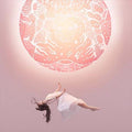 Woman in a white dress floating against a pink mandala background