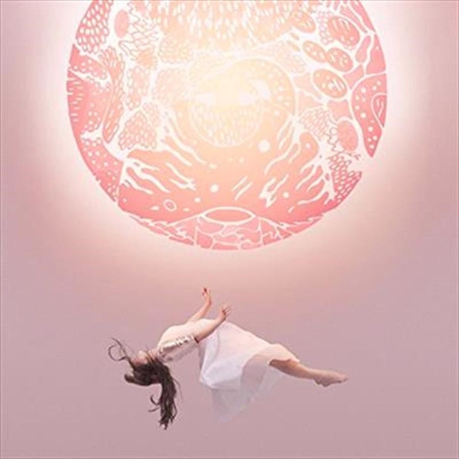 Woman in a white dress floating against a pink mandala background