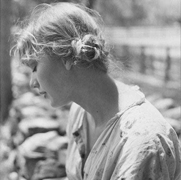 Black and white photo of a person with hair tied back, wearing a light-colored garment.